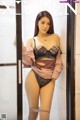 A woman in lingerie leaning against a glass door.