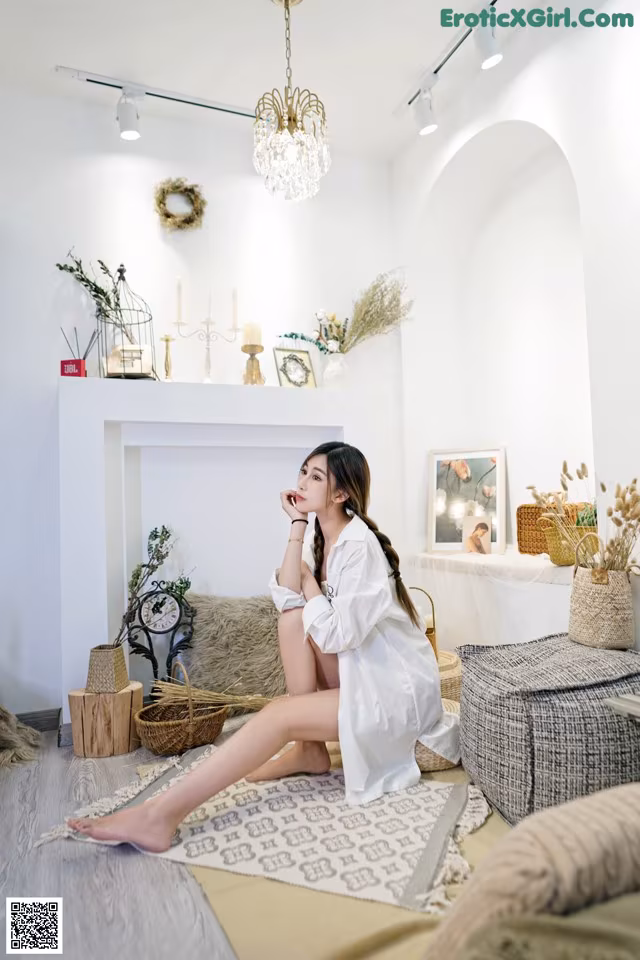 A woman sitting on the floor in front of a fireplace.
