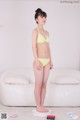 A woman in a yellow bikini standing on a scale.