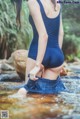 A woman in a blue bathing suit standing in a stream.