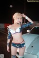 A woman in a bikini standing next to a car.