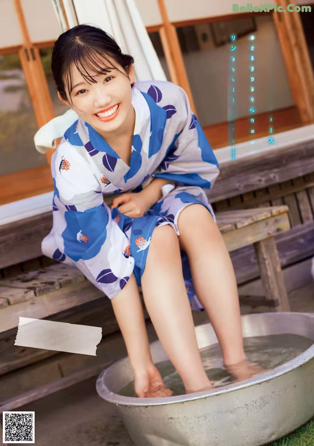 A woman in a blue and white kimono sitting in a metal tub.