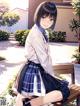 A girl in a school uniform sitting on a bench.