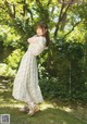 A woman in a white dress standing in the grass.