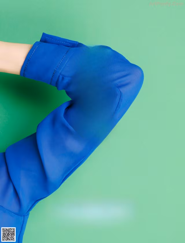 A woman in a blue dress with a green background.