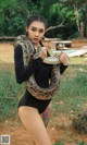 A woman in a black bodysuit holding a large snake.