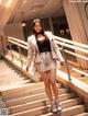 A woman in a white suit is standing on some stairs.