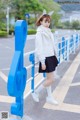 A young girl in a white coat and black skirt posing for a picture.