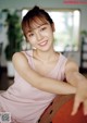 A woman in a pink tank top sitting on a couch.