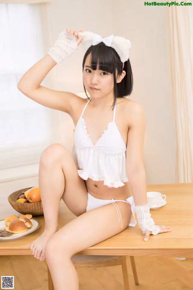A woman in a white bikini sitting on a table.