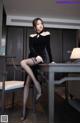 A woman in a black dress sitting at a table.