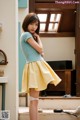 A woman in a blue shirt and yellow skirt posing for a picture.