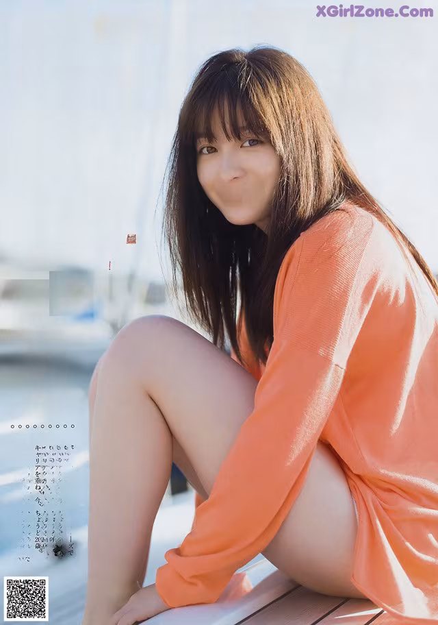 A woman sitting on top of a wooden dock.