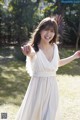 A woman in a white dress standing in a field.