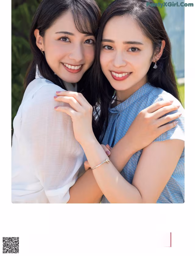 A couple of young women hugging each other in front of a building.