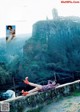 A woman laying on a stone wall next to a river.