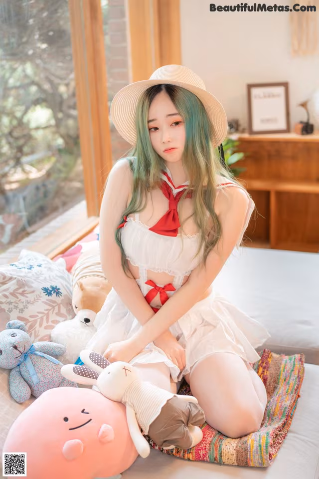 A woman sitting on a bed with stuffed animals.
