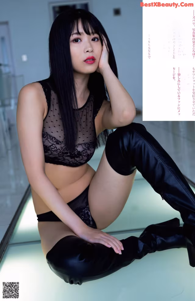 A woman in a black lingerie sitting on the floor.