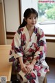 A woman in a kimono sitting on a wooden bench.