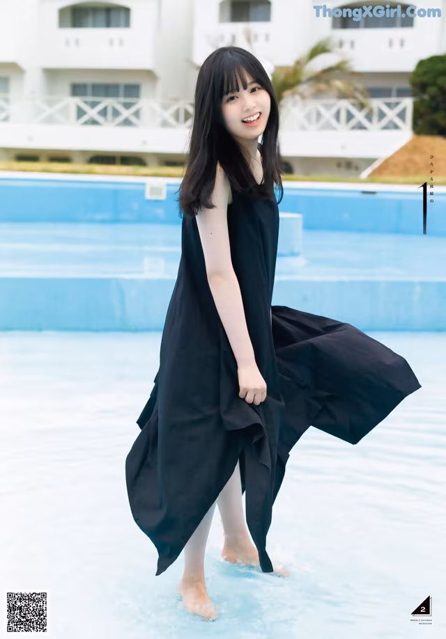 A woman in a black dress standing in a pool.