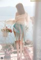 A woman standing on a balcony looking out over the ocean.