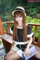 A woman sitting on a wooden bench wearing a hat.